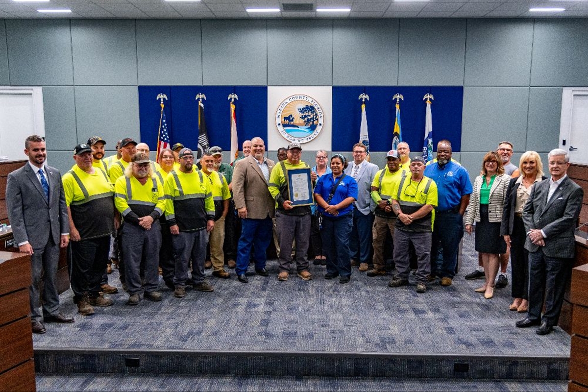 Marion County commissioners and Solid Waste staff gather in the commission chambers for a group photo, holding a framed proclamation honoring Waste and Recycling Workers Week.