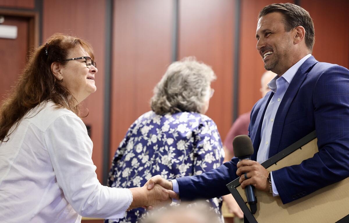 Mayor Marciano smiles and shakes hands with a community member inside the council chambers.