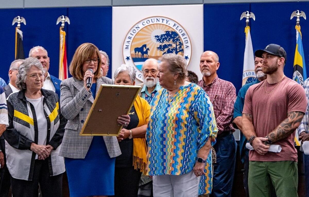 Marion County Commission Chairman Kathy Bryant reads a proclamation during a Faith and Family Month ceremony, surrounded by local community and faith leaders.