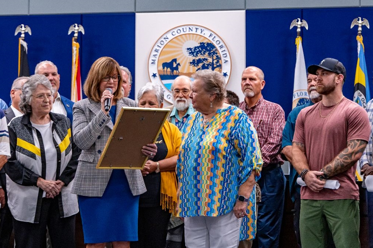 Marion County Commission Chairman Kathy Bryant reads a proclamation during a Faith and Family Month ceremony, surrounded by local community and faith leaders.