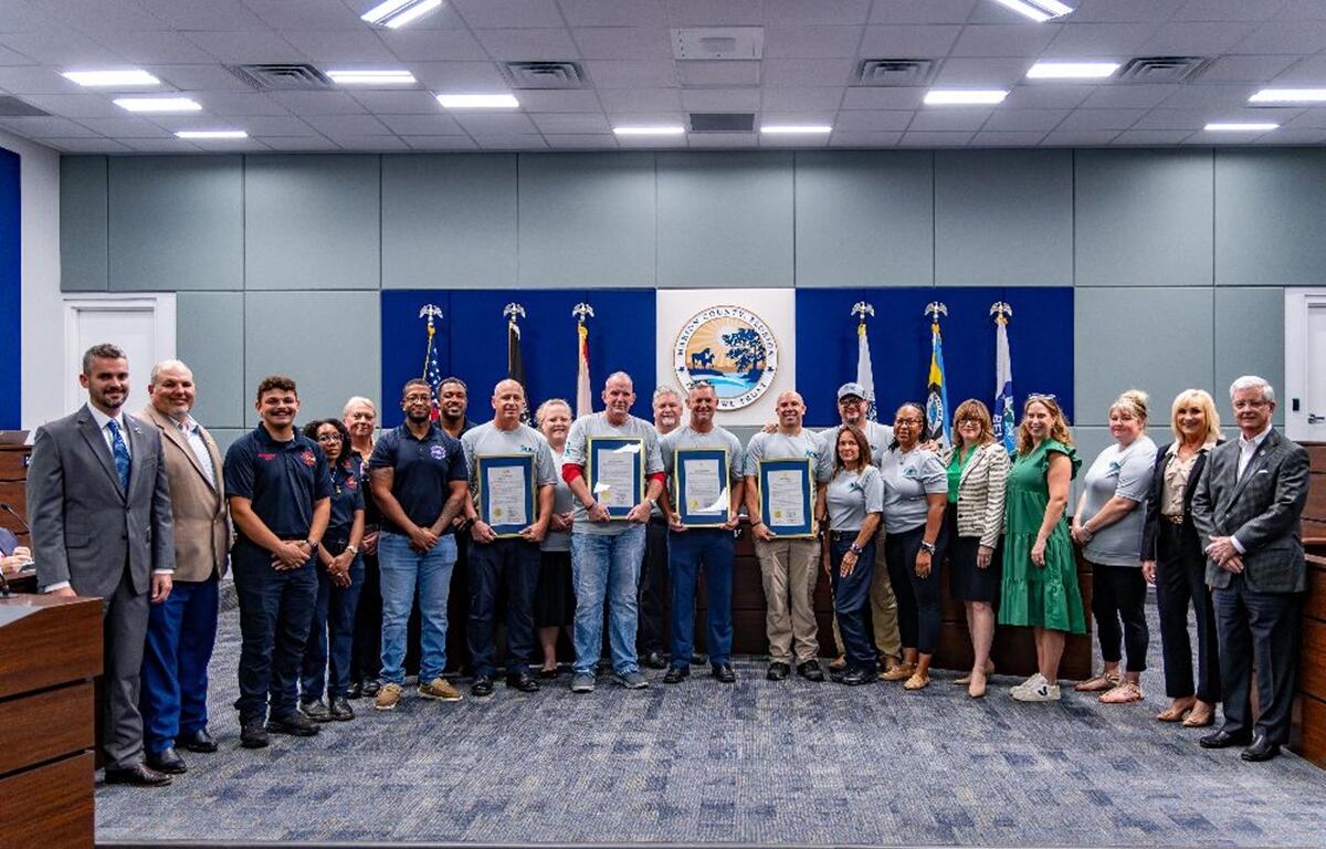 Group photo of Marion County commissioners, first responders, veterans, and supporters holding framed PTSD Awareness Day proclamations inside the commission chamber.
