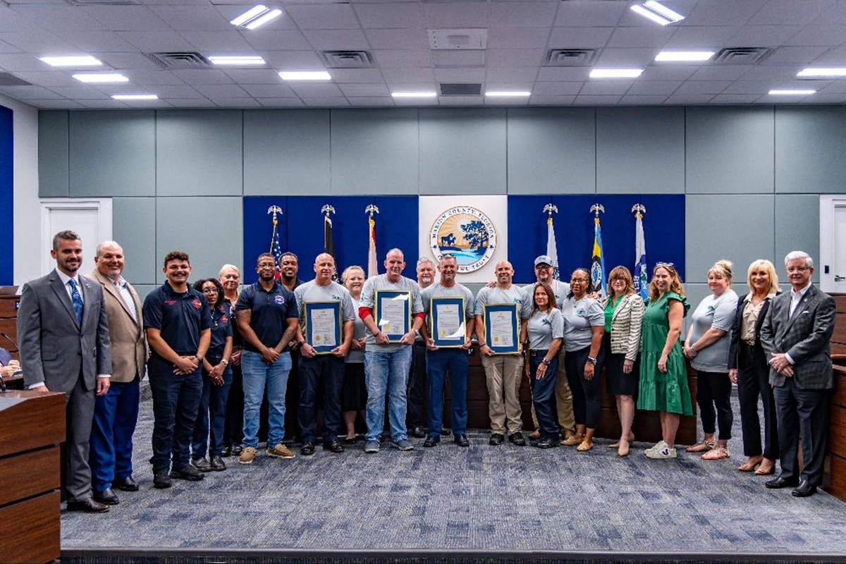 Group photo of Marion County commissioners, first responders, veterans, and supporters holding framed PTSD Awareness Day proclamations inside the commission chamber.