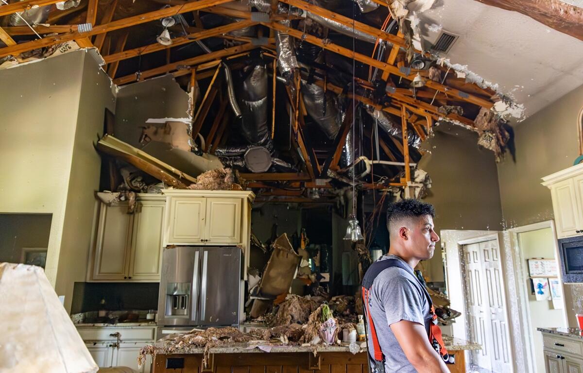 Firefighter stands inside heavily damaged kitchen of a NW Ocala home with collapsed ceiling and exposed ductwork after a residential fire.