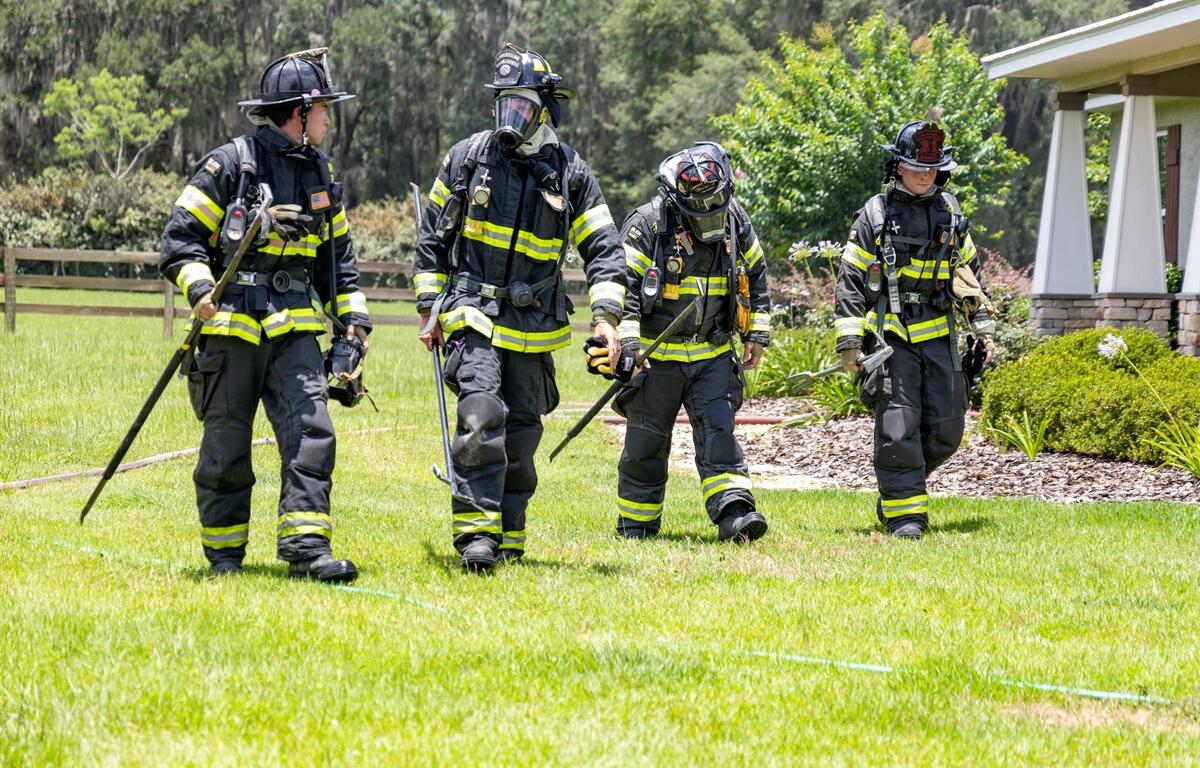 Four firefighters in full gear walk away from a house in NW Ocala after responding to a residential fire.