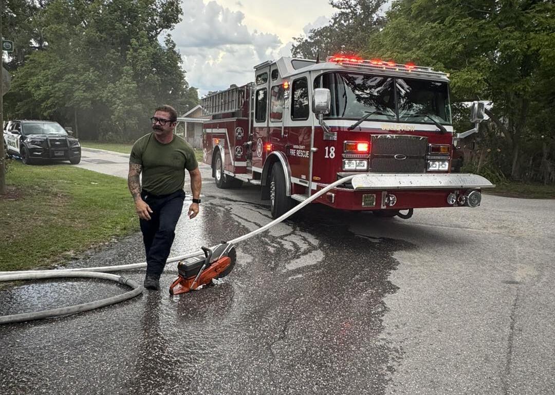 A fireman pulls a fire hose from a firetruck to extinguish a vehicle fire.