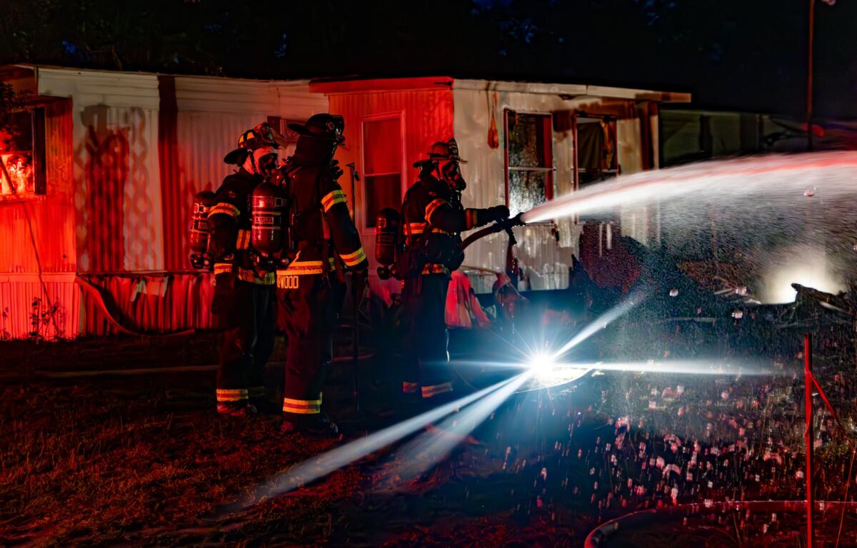 A firefighter stands near the remains of the structure, possibly surveying damage or checking for hazards.