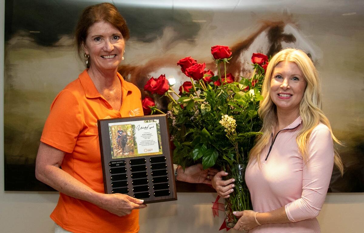 Meghan Magamoll receives the Unbridled Spirit Award from Consortium president Mary Chance while holding a bouquet of red roses in Ocala.