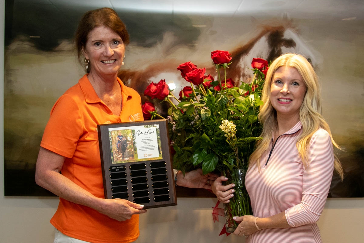 Meghan Magamoll receives the Unbridled Spirit Award from Consortium president Mary Chance while holding a bouquet of red roses in Ocala.