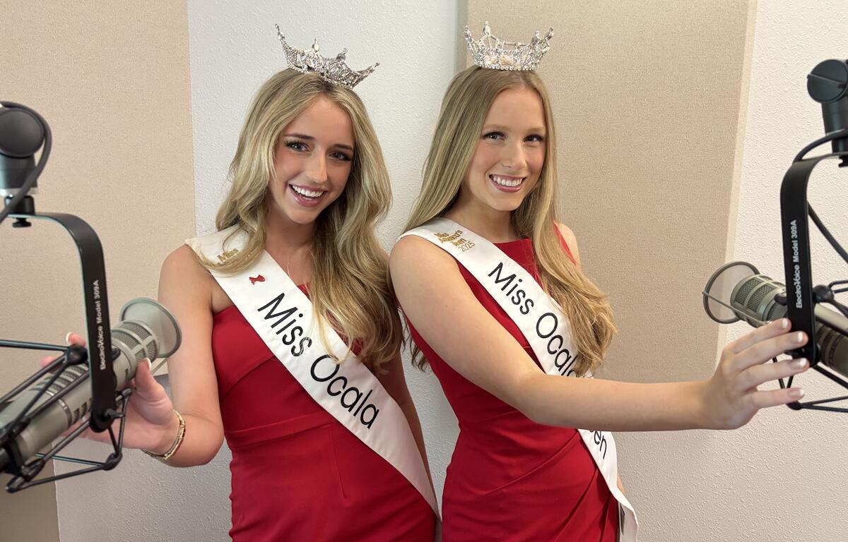 Miss Ocala 2025 Caroline Schapansky and Miss Ocala Teen 2025 Madalyn Covington smile beside studio microphones, wearing red dresses and crowns.