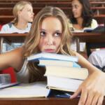Student overwhelmed by textbooks in a lecture hall while others talk in the background.