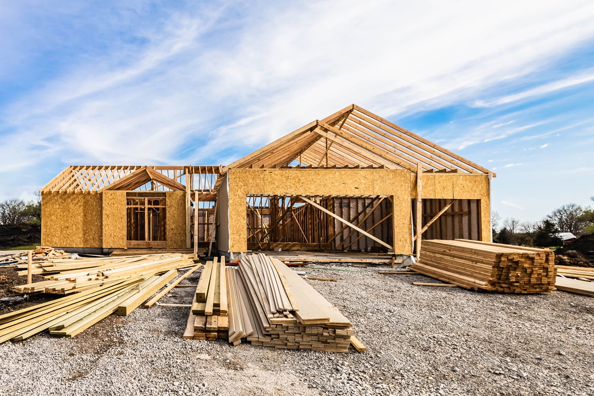 Partially built wood-frame house under construction on a clear day in Marion County, with lumber and building materials in the foreground.