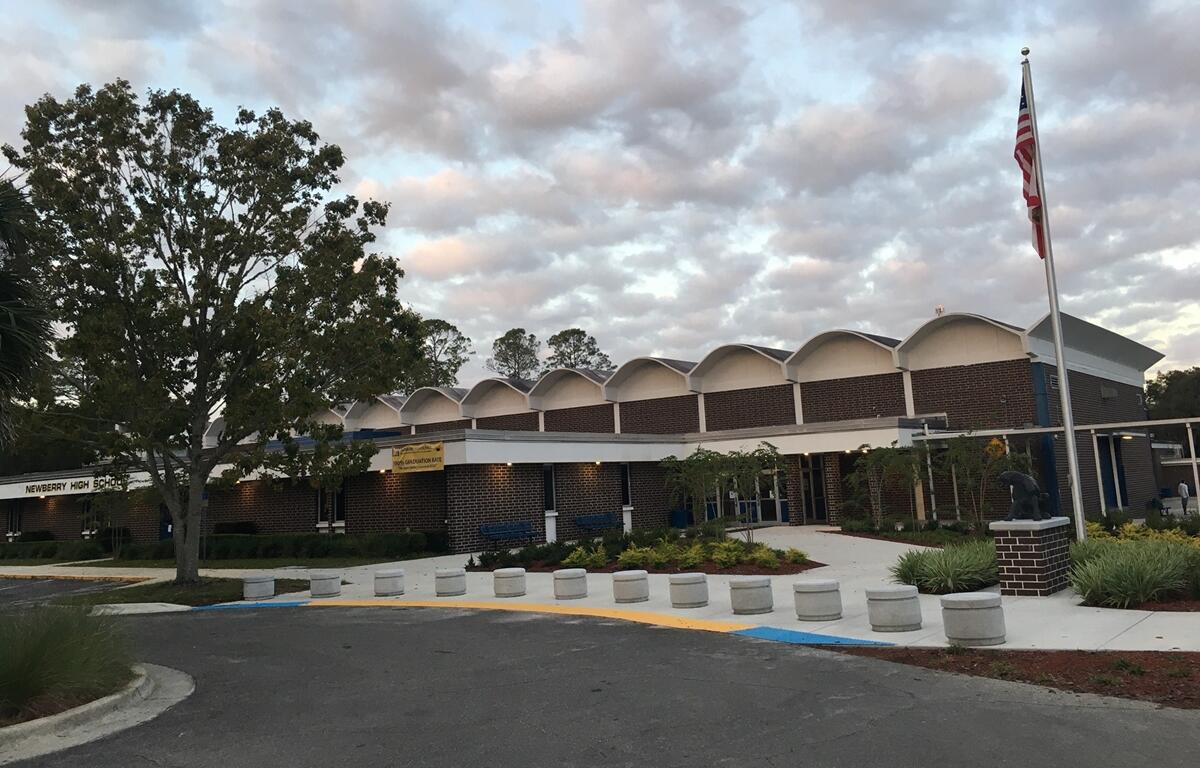 Exterior view of Newberry High School in Newberry, Florida, with American flag and landscaped entrance.