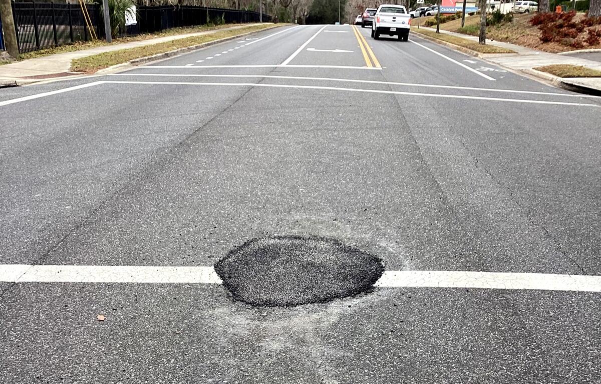Close-up view of a patched area on NW 8th Avenue in Gainesville where stormwater pipe damage occurred.