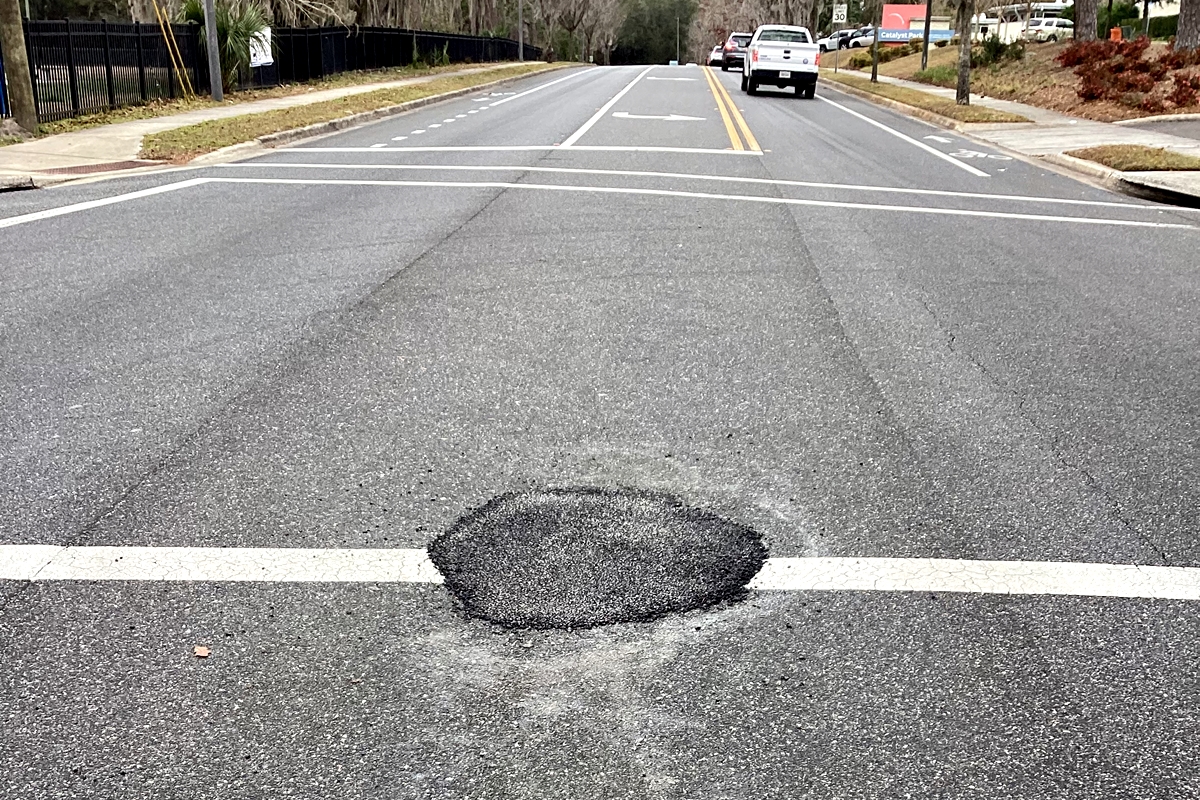Close-up view of a patched area on NW 8th Avenue in Gainesville where stormwater pipe damage occurred.