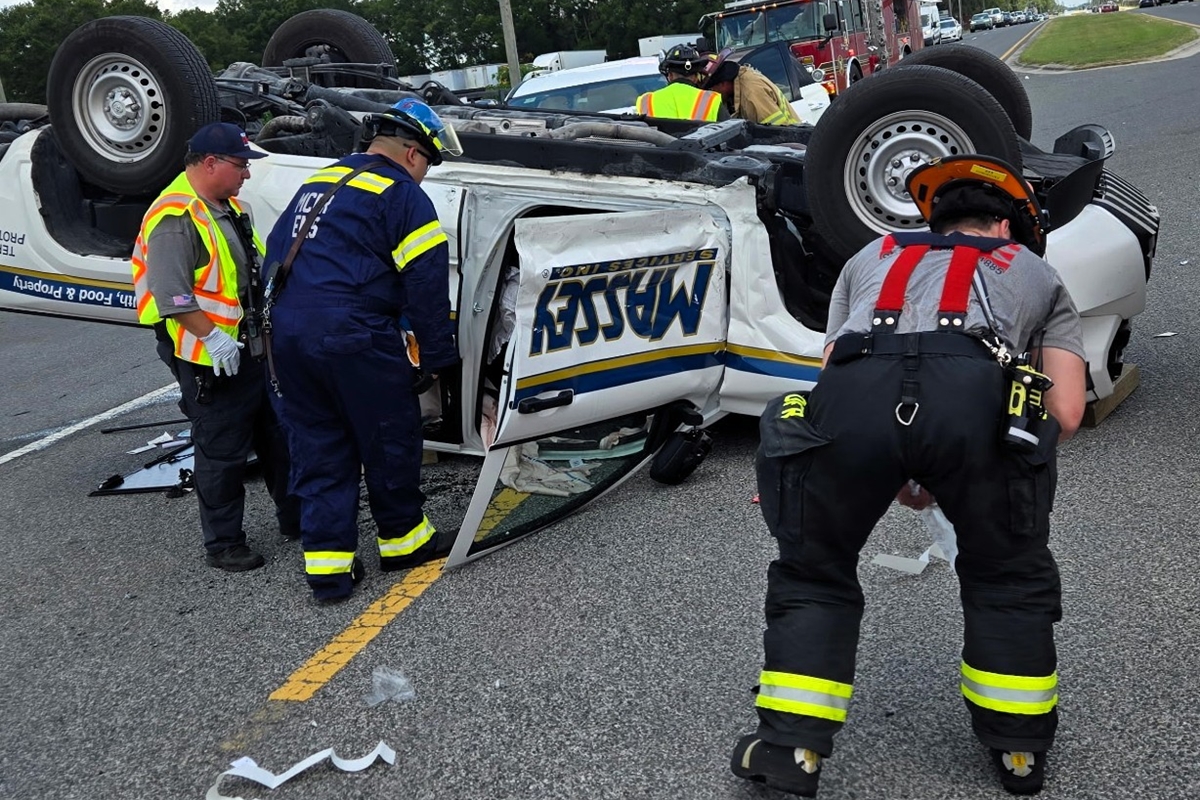 First responders surround an overturned white pickup truck on its roof during a vehicle rescue in Ocala.