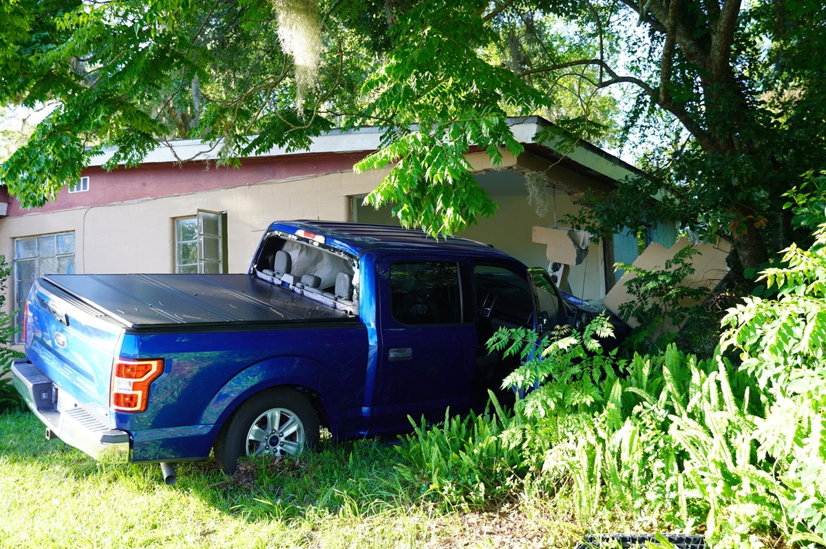 Blue pickup truck crashed into the corner of a home surrounded by trees and bushes in Ocala.