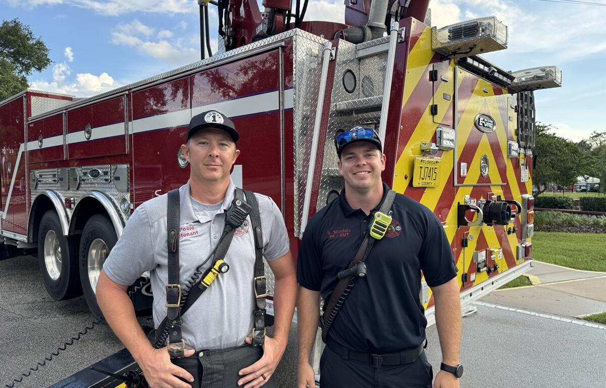 Two Ocala Fire Rescue members stand in front of a fire truck at the PTSD Awareness Walk.