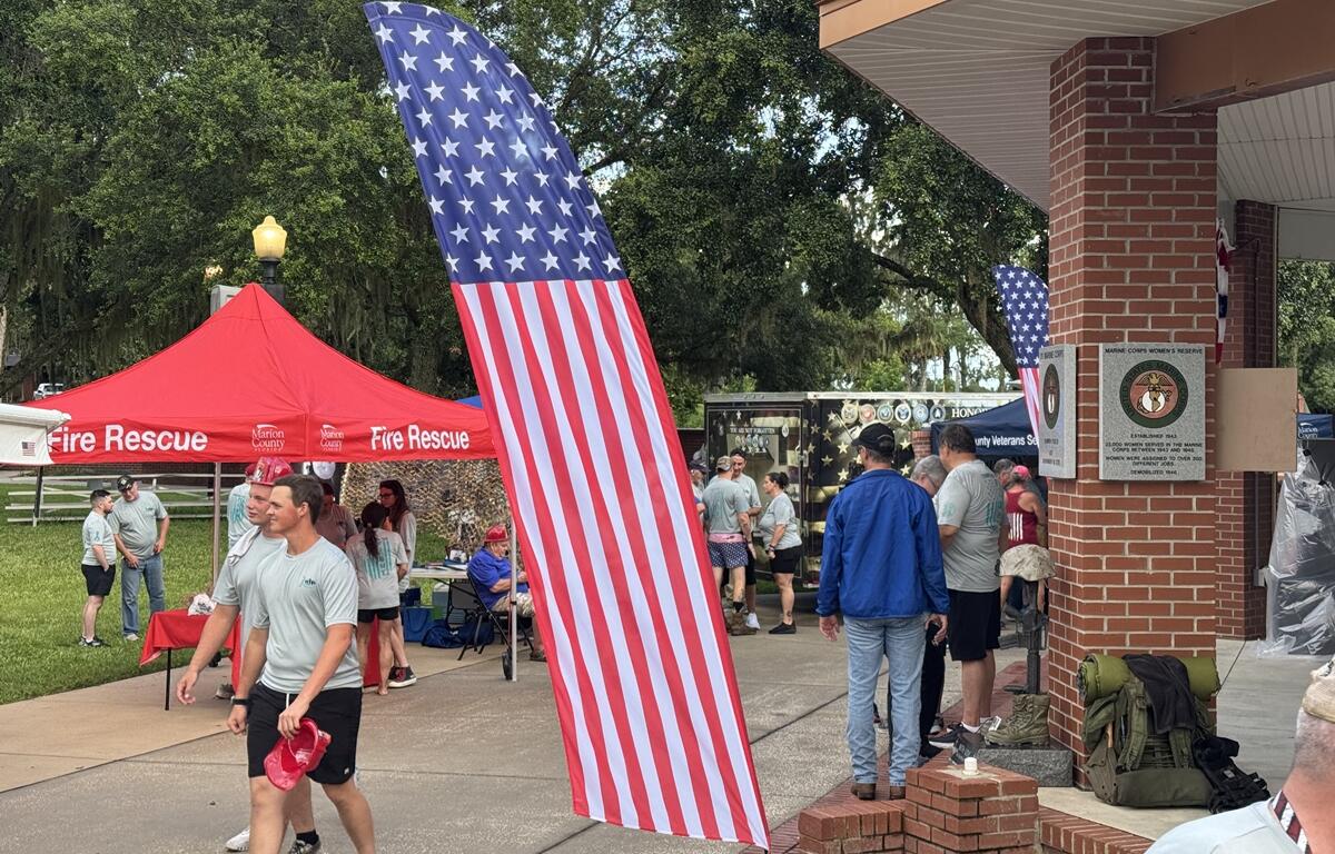 People gather near a Marion County Fire Rescue tent and memorial wall during the PTSD Awareness Walk in Ocala.