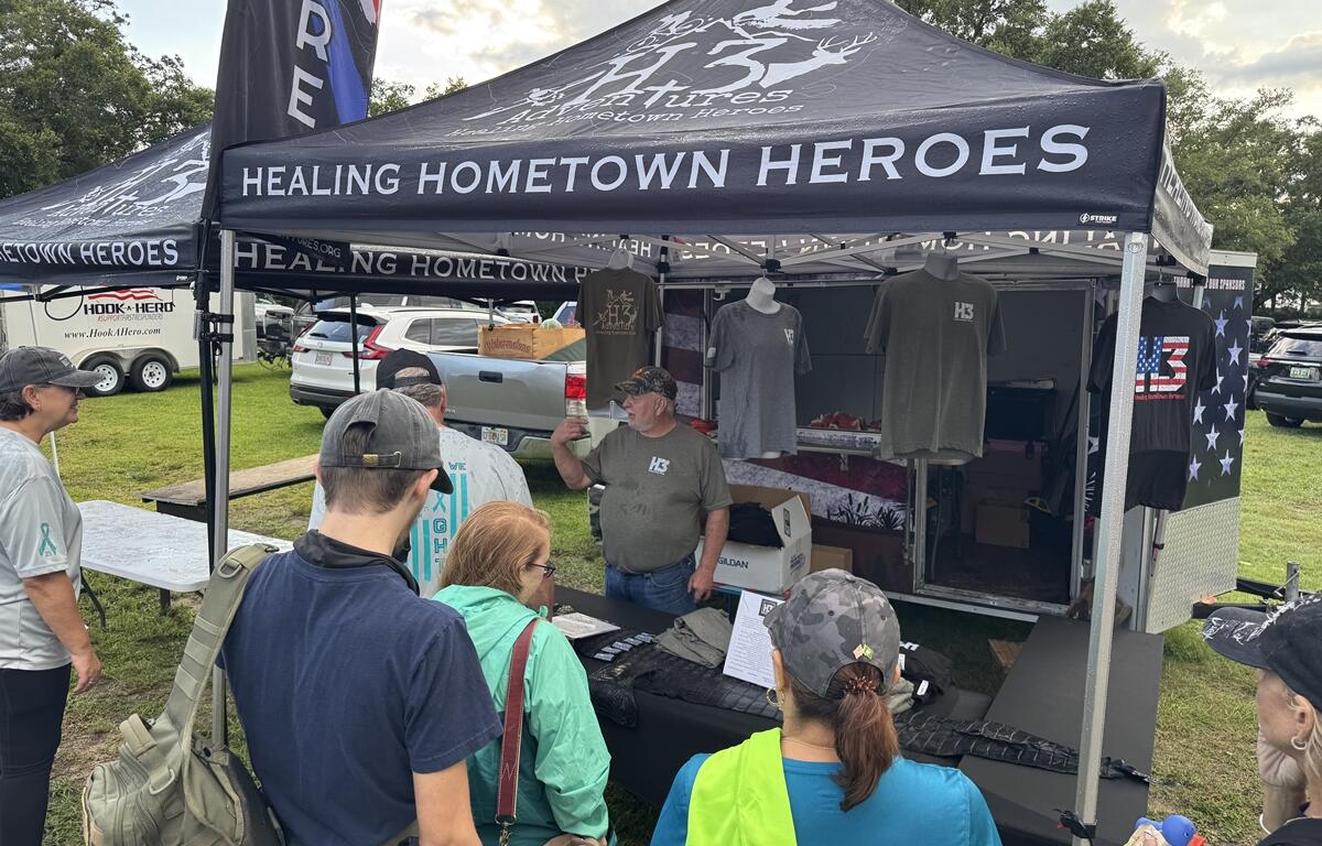 People gather around the Healing Hometown Heroes tent displaying T-shirts at the PTSD Awareness Walk in Ocala.