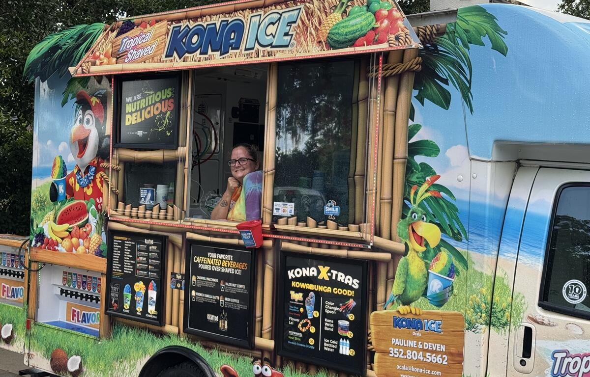 Kona Ice vendor smiles from a colorful shaved ice truck at the PTSD Awareness Walk in Ocala.