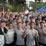 Smiling group of young men in PTSD Awareness Walk shirts pose in front of a crowd in Ocala.
