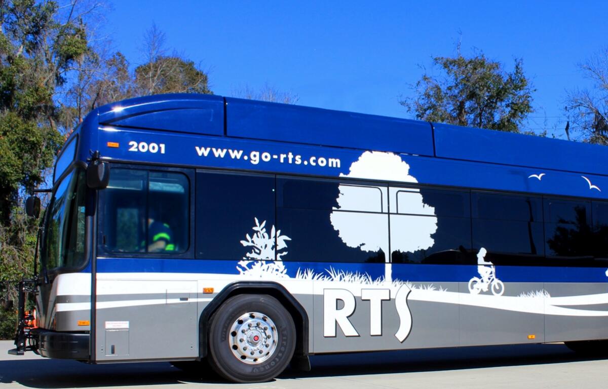 Blue and silver RTS public transit bus parked outdoors under a clear blue sky in Gainesville, Florida.