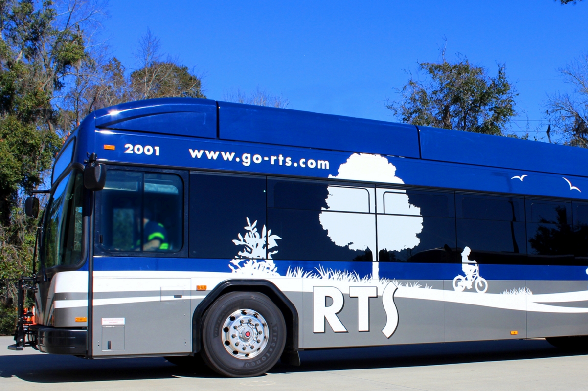 Blue and silver RTS public transit bus parked outdoors under a clear blue sky in Gainesville, Florida.