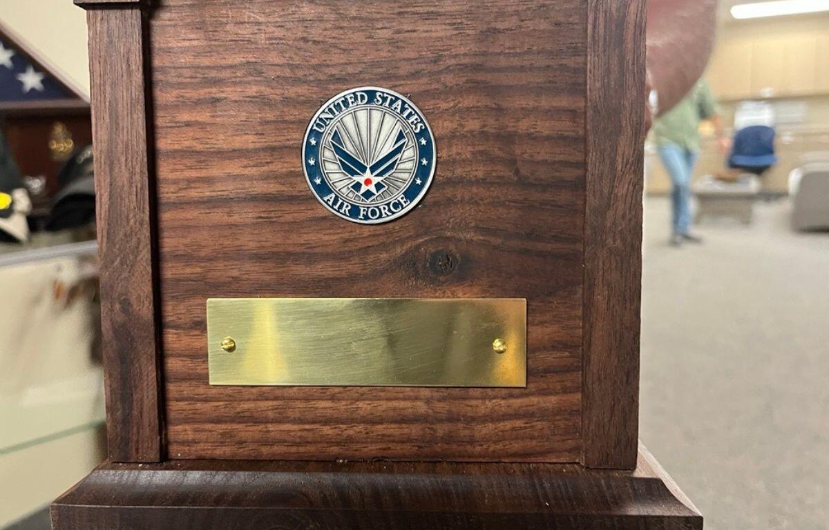 A wooden box, with a circle with the U.S. Air Force's insignia attached to the box, along with a metal piece underneath the circle.
