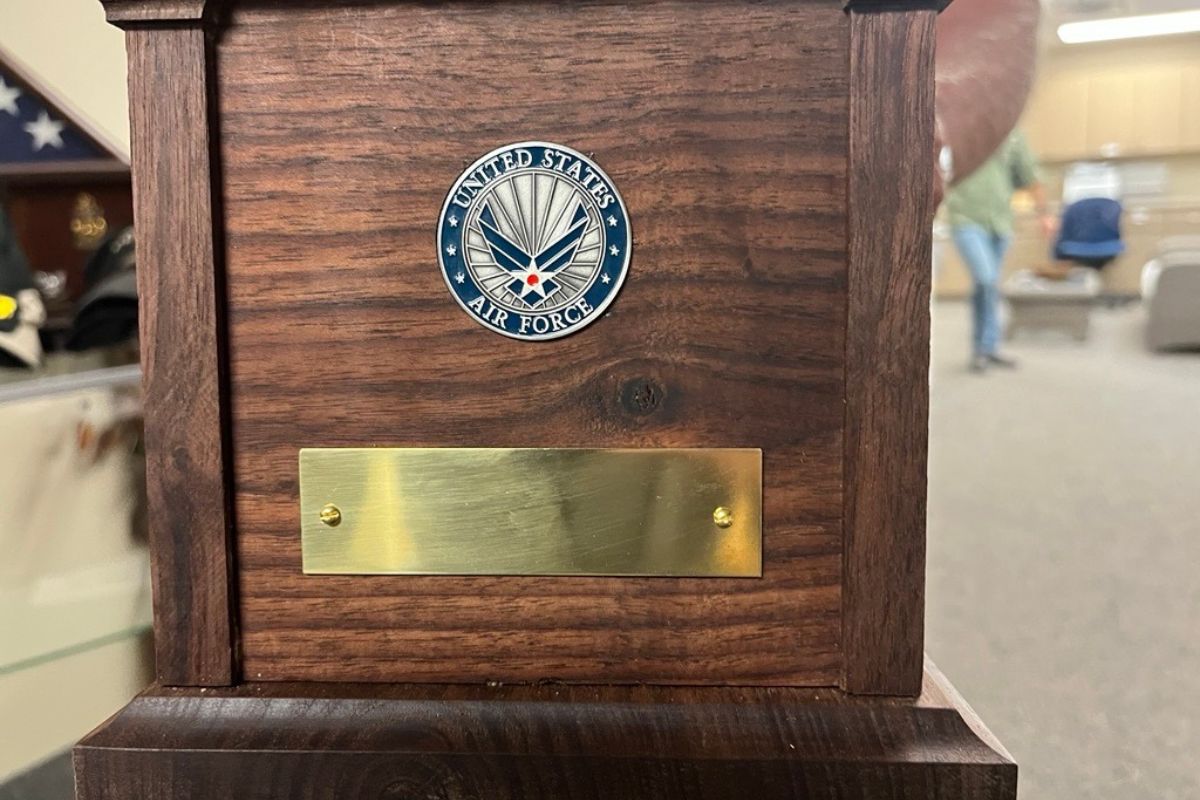 A wooden box, with a circle with the U.S. Air Force's insignia attached to the box, along with a metal piece underneath the circle.