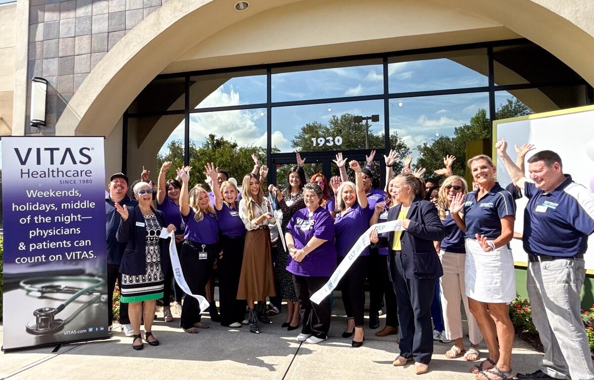 Group of VITAS Healthcare employees and local leaders standing outside the new Ocala office, cheering during a ribbon-cutting ceremony.