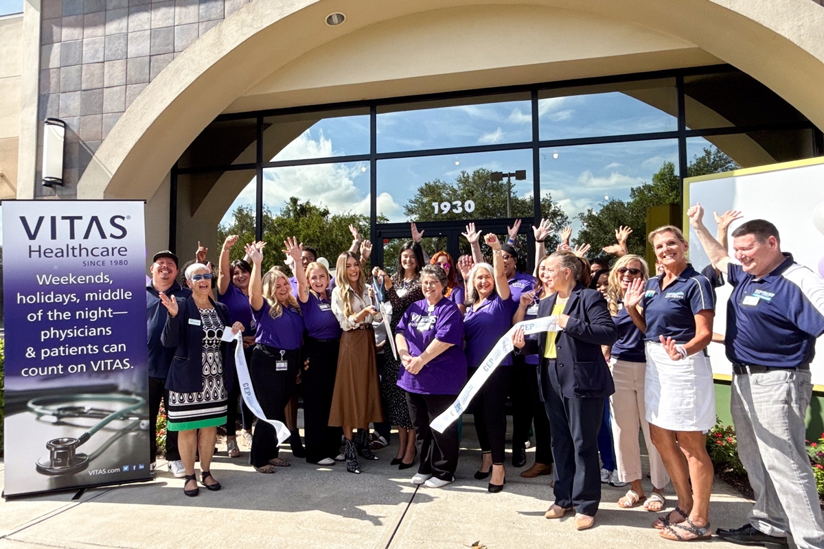 Group of VITAS Healthcare employees and local leaders standing outside the new Ocala office, cheering during a ribbon-cutting ceremony.