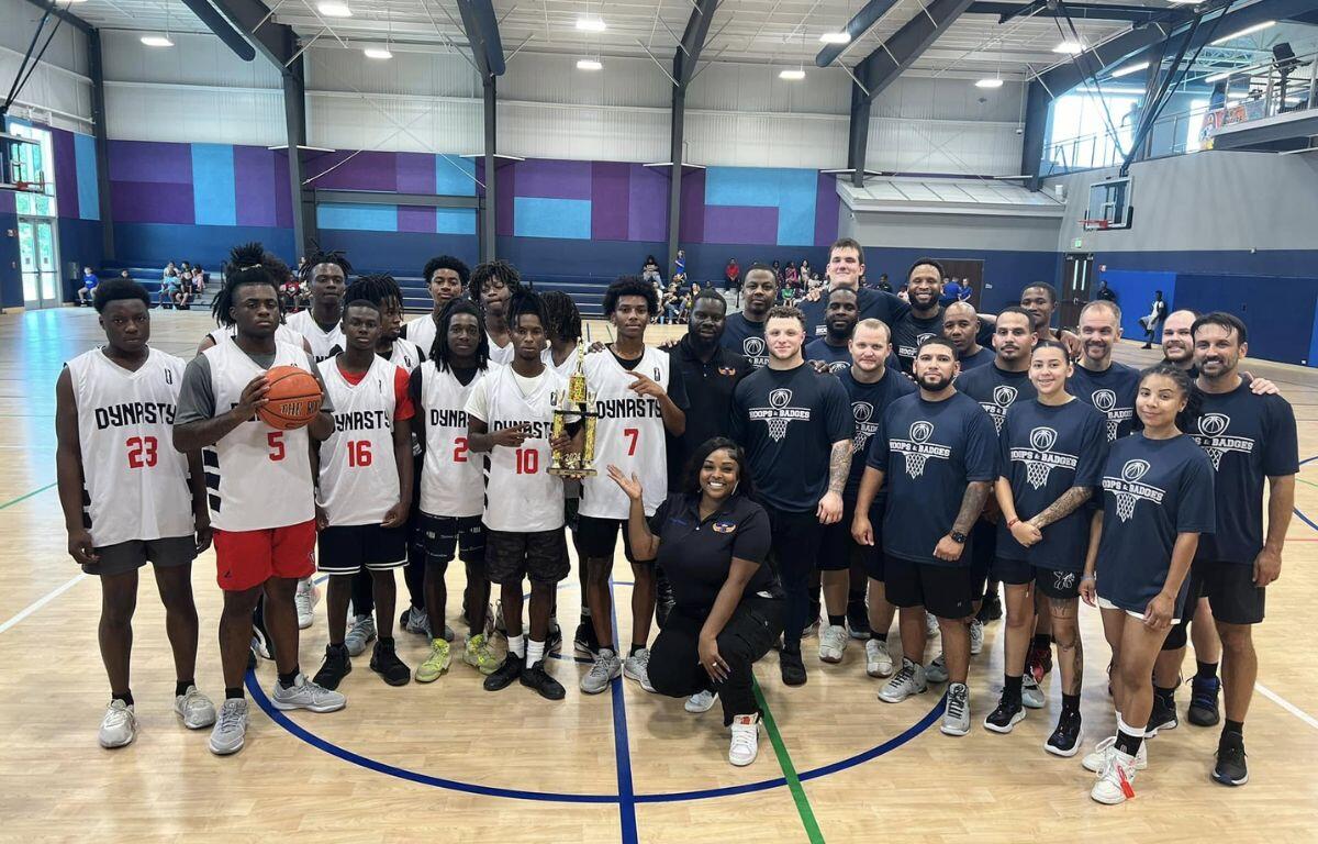 A group of people who just played a basketball game. The people dressed in blue are police officers, while the people dressed in white are youth basketball players.