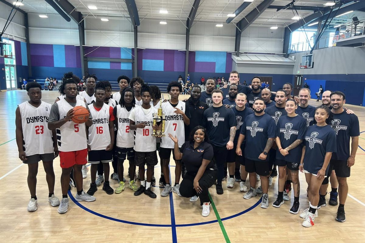 A group of people who just played a basketball game. The people dressed in blue are police officers, while the people dressed in white are youth basketball players.