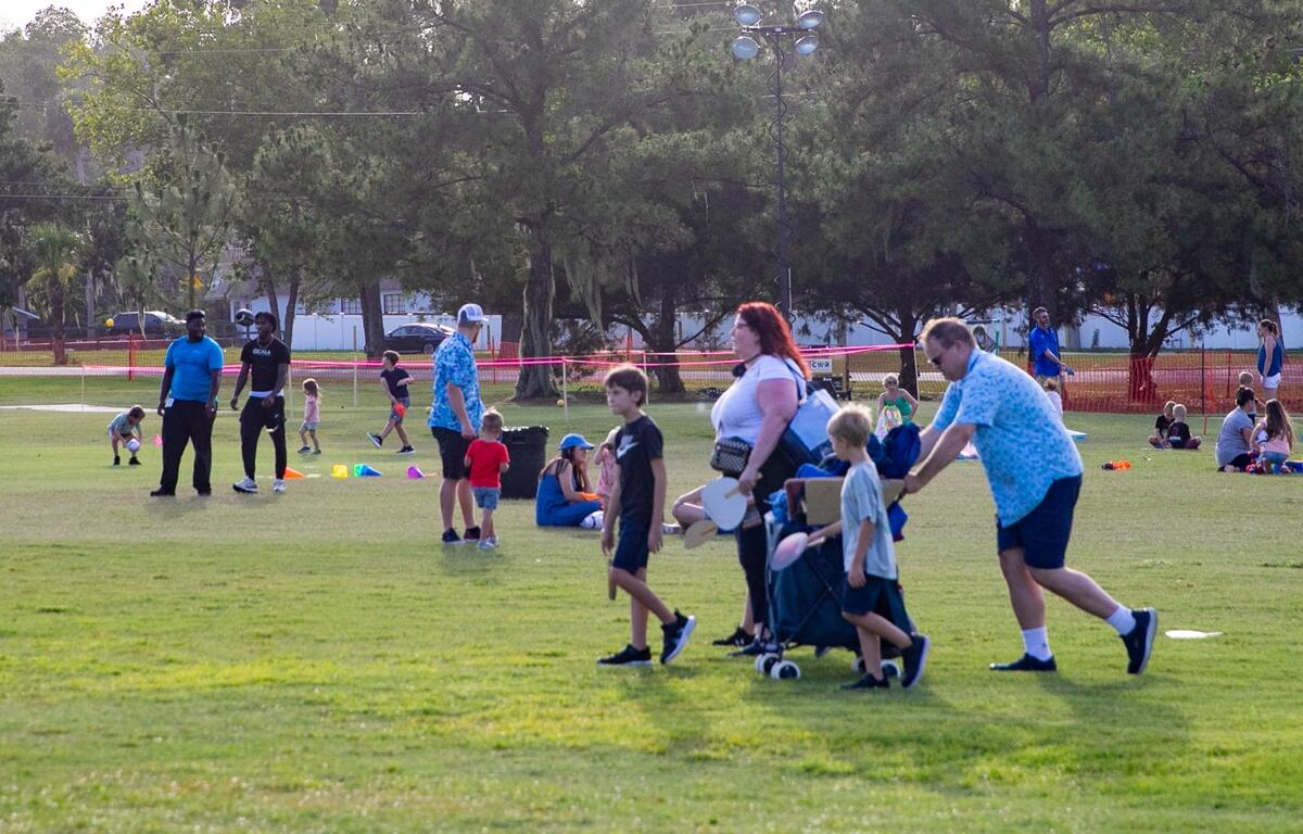 Parents and children walk and play in the kids activity zone on the golf course during Symphony Under the Stars.