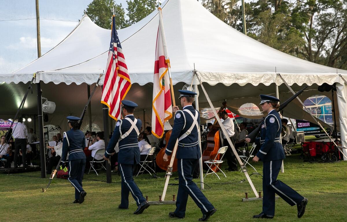 Forest High School Air Force JROTC cadets carry the U.S. and Florida flags past the orchestra tent during Symphony Under the Stars.