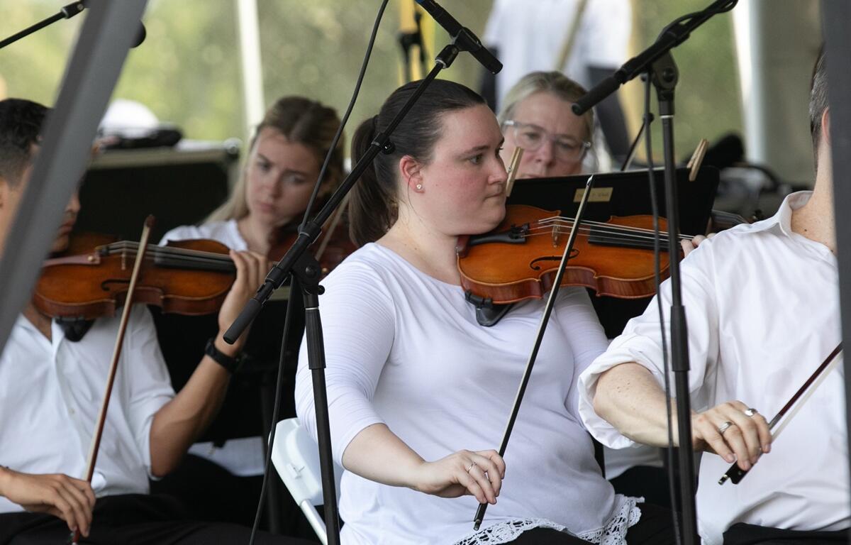 Close-up of violinists playing in the Ocala Symphony during the outdoor performance.