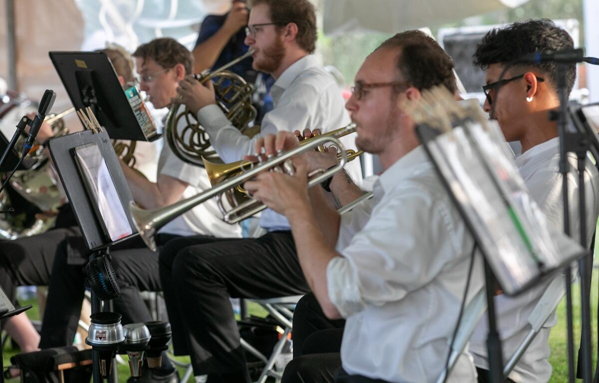 Trumpet and French horn players read sheet music and perform during the concert.