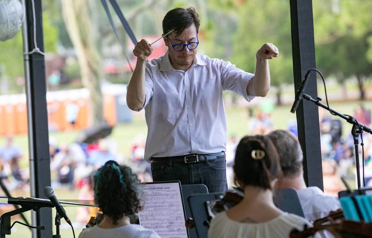 Conductor Matt Wardell raises his baton while leading musicians at the outdoor evening performance.