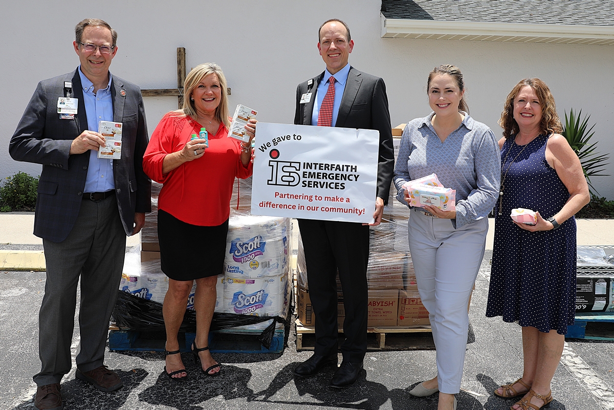 Five representatives from HCA Florida Healthcare and Interfaith Emergency Services pose with donated hygiene items outside Interfaith’s Ocala building.