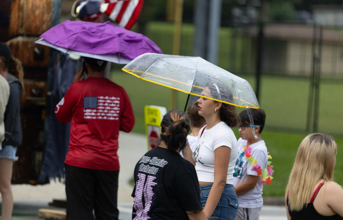 People walk under umbrellas during rain at Ocala's Fourth of July event.