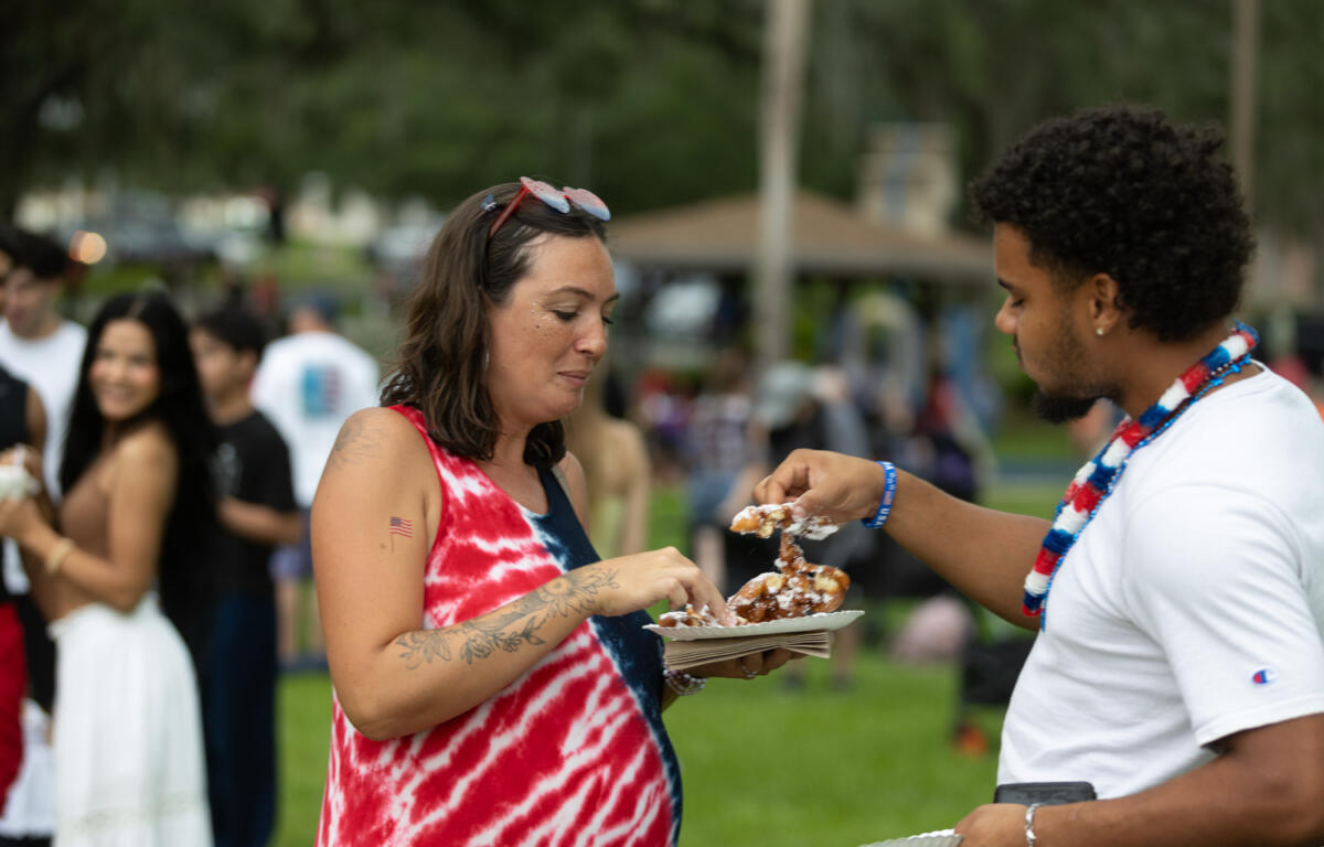 Man and woman share funnel cake at Fourth of July celebration in Ocala.