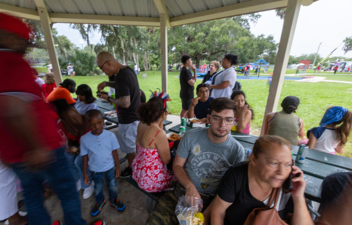 People sit and eat under a park pavilion during a rainy Fourth of July event in Ocala.
