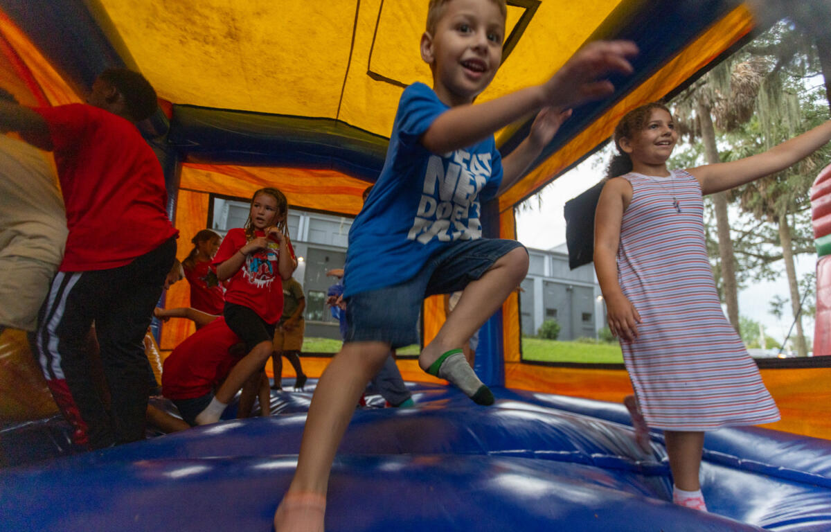 Kids smiling and jumping inside a colorful bounce house during a holiday event.