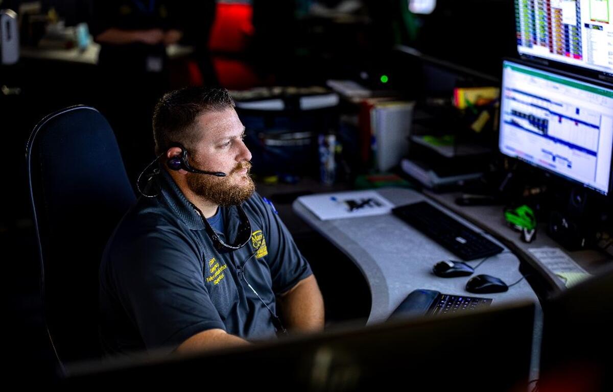 Kyle Coburn wears a headset while handling a 911 emergency call at his computer station.