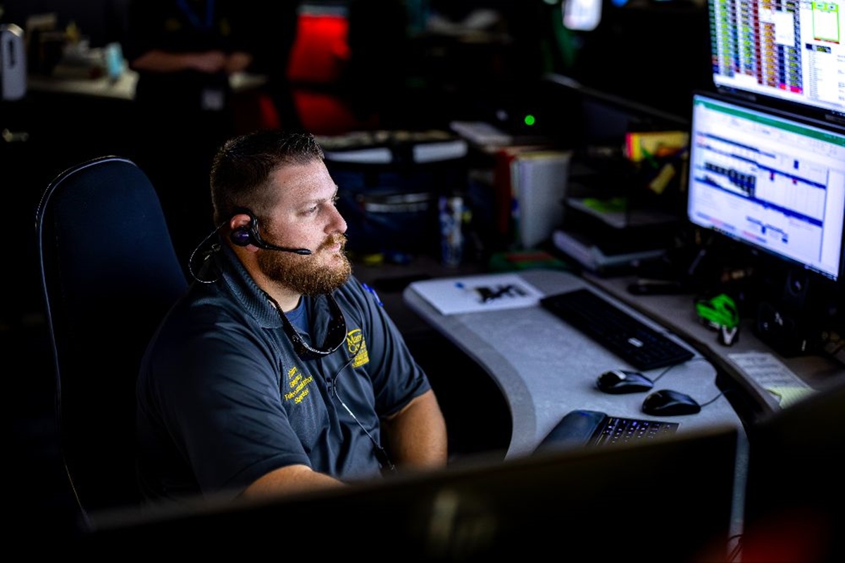 Kyle Coburn wears a headset while handling a 911 emergency call at his computer station.