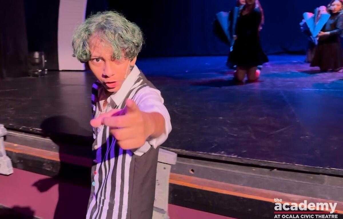 Youth actor dressed as Beetlejuice points toward the camera during a rehearsal at Ocala Civic Theatre.