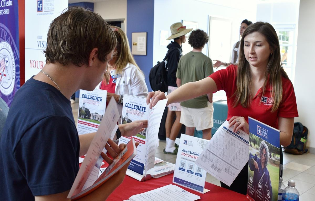 College of Central Florida staff member handing admissions flyer to student at expo table