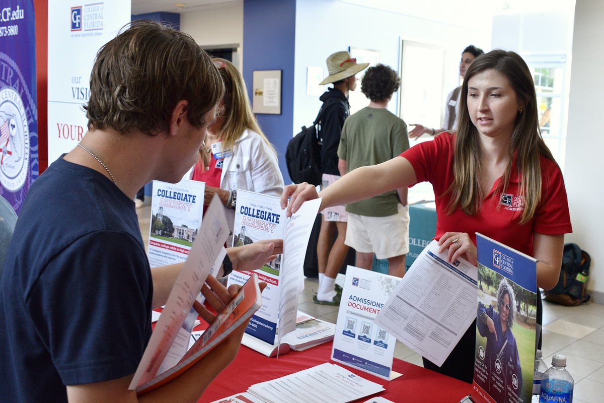 College of Central Florida staff member handing admissions flyer to student at expo table