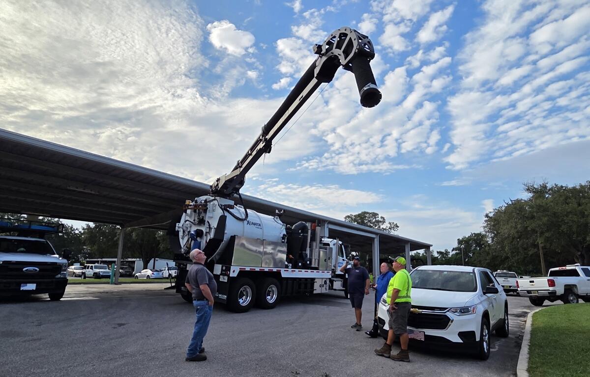 Ocala city workers watch Vactor truck demonstration with extended vacuum arm.