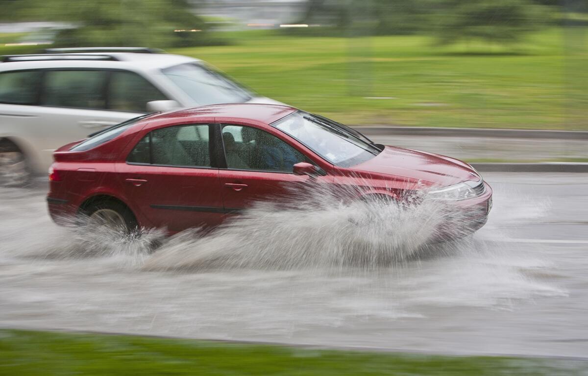Red car drives through floodwater in Ocala during heavy rain from low-pressure system